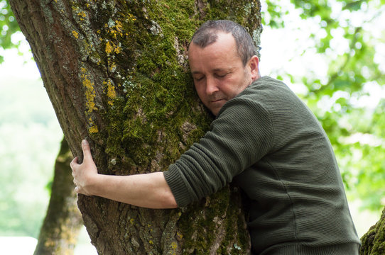Portrait of man hugging a tree in a forest
