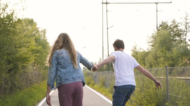 Couple skateboarding together and holding hands