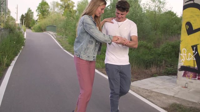 Young man teaching his girlfriend how to skate