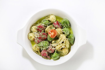 basil sauced pasta with vegetables top view isolated background