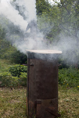 Fototapeta na wymiar Smoke billows from a stainless steel outdoor furnace.