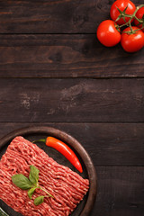 raw minced meat on paper, ingredients for burger with tomato, pepper, onion, spices and seasonings on black background. Top view and copy space