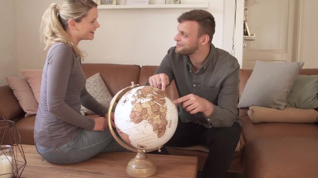 Couple looking at globe and having fun together