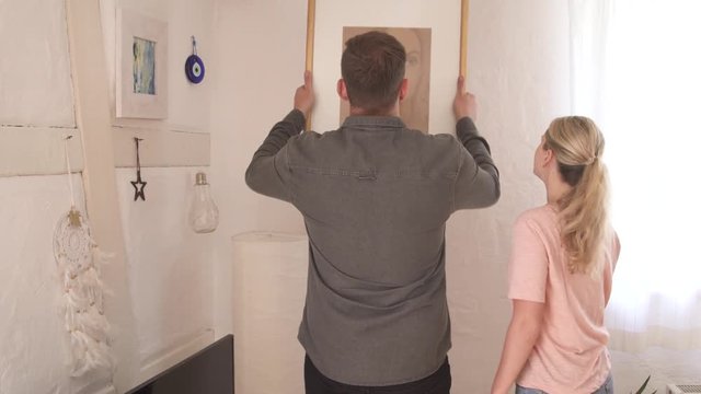 Couple hanging up a picture in their home