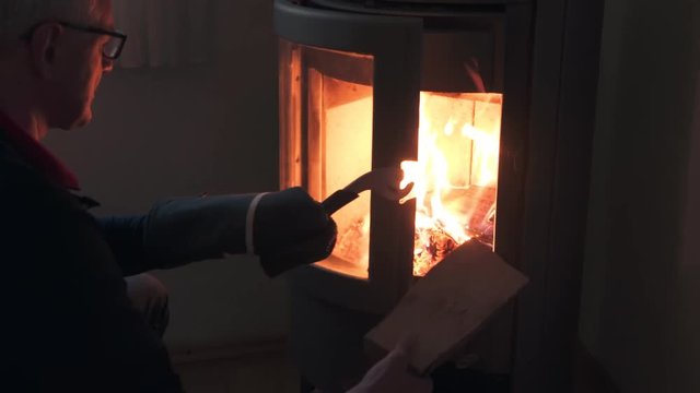 Man putting a log into fire of a wood stove
