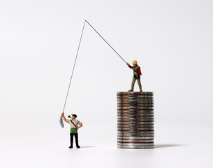 Miniature people fishing and piles of coins. The concept of income inequality.