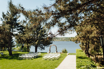 beautiful arch for the wedding ceremony in the park with white chairs for guests