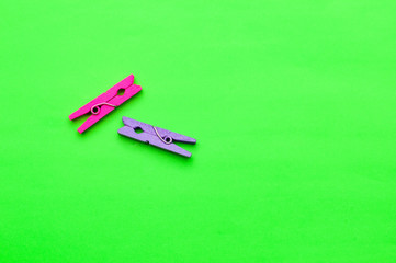 two small colorful wooden clothespin on a green background