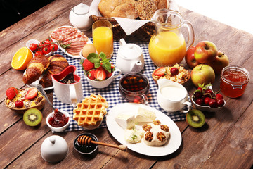 Huge healthy breakfast on table with coffee, orange juice, fruits, waffles and croissants. Good morning concept.