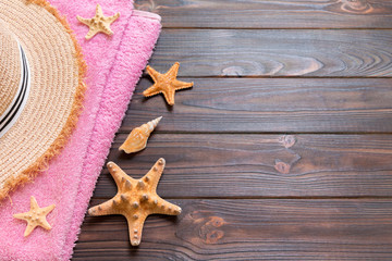 Straw hat, pink towel and starfish On a dark wooden background. top view summer holiday concept with copy space