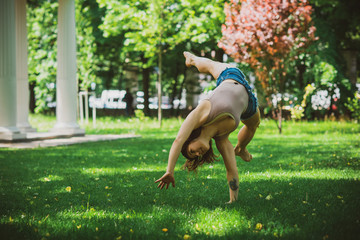 Freedom concept. Happy woman does tricks and jumps in city park, nice girl with good mood having fun, lifestyle 