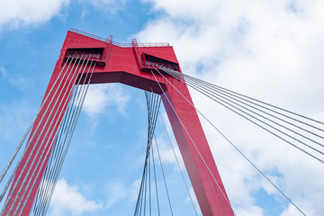 Obraz premium Willemsbrug bridge red cable bridge against blue sky and white clouds, Rotterdam, Netherlands