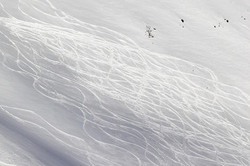 Snowy off-piste ski slope with traces from skis and snowboards at winter