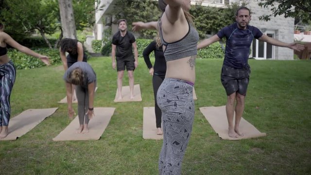 Barefoot sporty people practicing yoga outdoor. Sportive men and women standing on yoga mats and performing yoga poses outdoor. Yoga concept