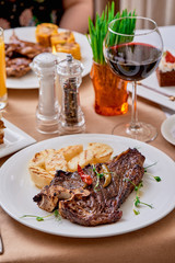 T-Bone steak serving with grilled vegetables on a white round plate on a table in the restaurant. Close up