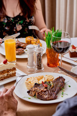 T-Bone steak serving with grilled vegetables on a white round plate on a table in the restaurant. Close up