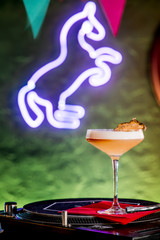 Yellow cocktail with white foam, decorated slice dry pineapple, in elegant glass in the restaurant...