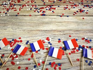 The national holiday of July 14 is a happy Independence Day of France, Bastille Day, the concept of patriotism, memory, place for text, confetti and flags on a wooden table, horizontal