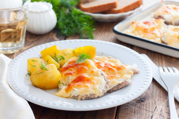 Portion of pork chop with cheese and boiled potatoes on a wooden table, horizontal