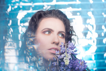 Beautiful young model fashion girl in flowers with hairstyle .  Blue background . Fashion, Cosmetics & Perfumes 