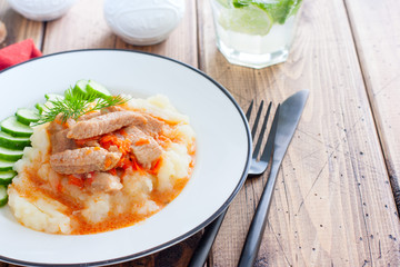 Pork slices with tomato sauce and mashed potatoes on a wooden table, horizontal, copy space