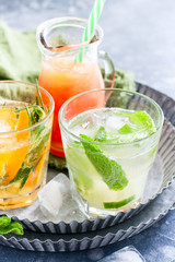 Mojito on the background of summer cold drinks with citrus fruits: lemonade, oranzhad, grape juice and mandarin juice, selective focus