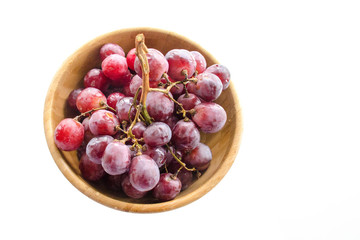 Isolated juicy clusters of large red grapes in a wooden bowl