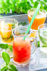 Cold grapefruit juice on a background of summer cold citrus drinks: mojito, lemonade, orange juice, tangerine juice, selective focus