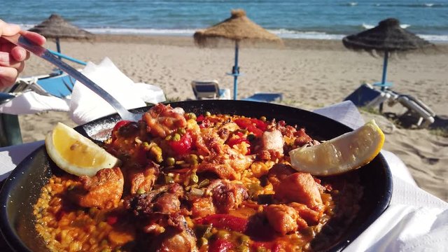 scooping paella on the beach with a ladle, summer vacation shot, footage filmed in Marbella, Spain. 
Costa del sol holiday Spanish food