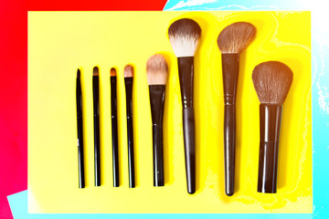 Various makeup brushes on a bright yellow background, close-up,