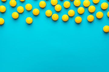 many balls for table tennis on turquoise blue background. flat lay image of many yellow table tennis balls with copy space. minimalist photo of yellow ping-pong equipment - obrazy, fototapety, plakaty