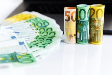 Banknotes of different denominations lie near the laptop. Shopping time