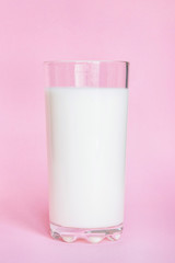 Glass with milk on pink background