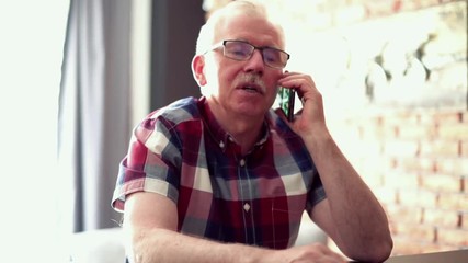 Senior man talking on cellphone at home