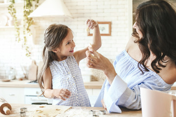 Happy mother with daughter preparing cookies in kitchen at home