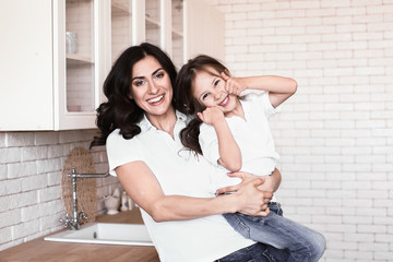 Happy mother with daughter in kitchen at home