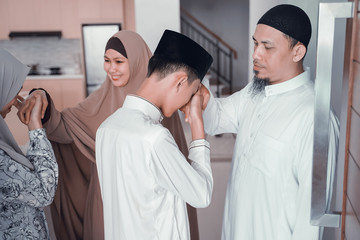 Fototapeta premium asian muslim parent shake hand in idul fitri eid mubarak celebration. family islam tradition