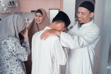 Obraz premium asian muslim parent shake hand in idul fitri eid mubarak celebration. family islam tradition