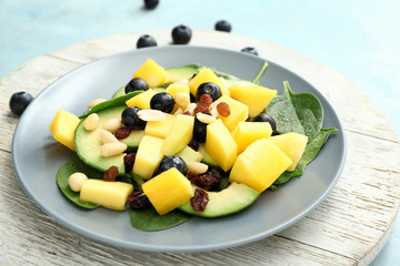 Plate with tasty mango salad on table