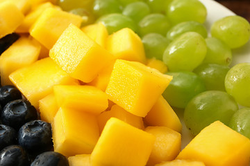 Tasty mango with berries and grapes, closeup