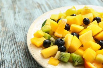 Plate with tasty mango salad on wooden table