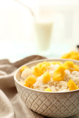 Bowl with tasty mango and boiled rice on table
