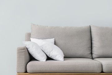 Soft pillows on sofa against light wall