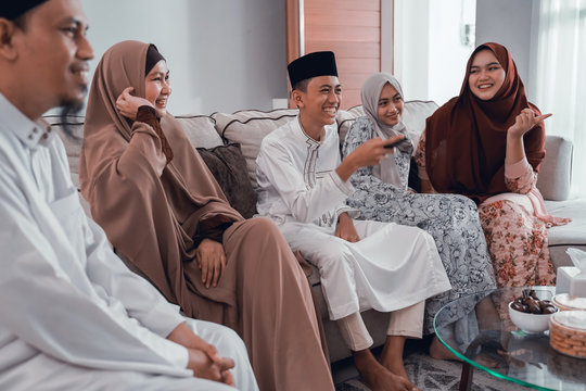 Happy Muslim Family Watching Tv Together At Home Livingroom