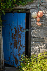 An open broken painted door held open with a piece of string of a traditional stone building in Ireland, nobody in the image