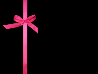 Bows from pink satin ribbon vertically on black background with copy space. Greeting card concept