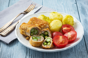 Roasted asparagus stuffed pork tenderloin served with potatoes and tomatoes.