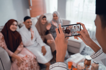 male muslim taking picture of his family while sitting on a couch at home in eid mubarak
