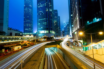 Fototapeta na wymiar Street traffic at twilight sunset in Hong Kong. Office skyscraper buildings and with blurred car light trails. Hong Kong, Special administrative region in China.