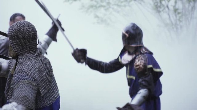 Four knights of medieval age are having a sword fight in the smoke